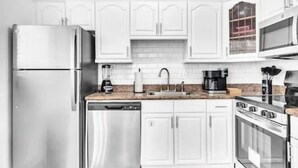 A modern kitchen with white cabinetry, stainless steel appliances, and a microwave. - Tranquil Waterside Retreat (Oakland Park)