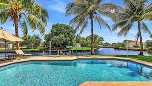 A swimming pool with palm trees and a view of a lake. - Tranquil Waterside Retreat (Oakland Park)