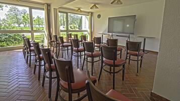 A conference room with a large screen, multiple chairs, and a brick floor.