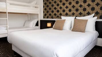 Habitación de hotel con una litera, una cama grande y un cabecero estampado.