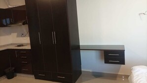 A bedroom with a large wardrobe, a bed, and a small bedside table. - Monument Suites  (Amman)