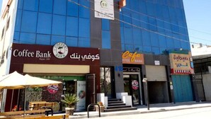 A modern building with a Coffee Bank sign on the ground floor. - Monument Suites  (Amman)