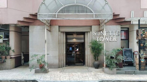 The entrance to Sunette Tower with a covered entrance and potted plants. - Sunette Tower Makati (Makati)