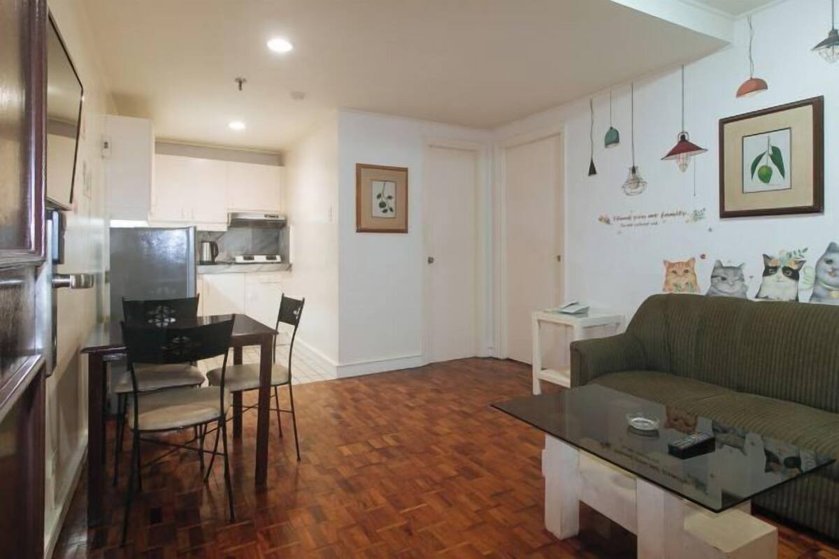 A compact living space with a dining area, a sofa, and a kitchen in the background.