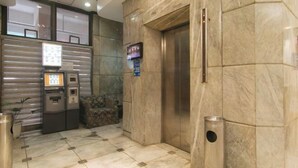 A lobby with a reception desk, an elevator, and a trash bin. - Sunette Tower Makati (Makati)