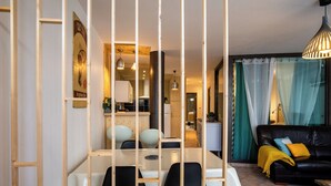Una sala de estar moderna con comedor, un sofá de cuero negro y una cocina al fondo.