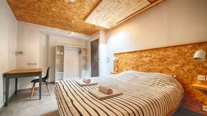 Un dormitorio con techo de madera, cama con ropa de cama a rayas, un escritorio y una silla.