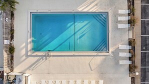 An aerial view of a rectangular swimming pool with two lanes, surrounded by a concrete deck and shaded by palm trees. - Dog Friendly Getaway Steps to Beach & Pool, Coffee Bar, K Bed, Putting Green (Panama City Beach)