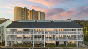 A multi-story hotel with balconies and a parking lot in front. - Dog Friendly Getaway Steps to Beach & Pool, Coffee Bar, K Bed, Putting Green (Panama City Beach)