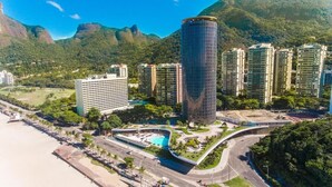 Un moderno complejo hotelero con varios edificios altos, una piscina y acceso directo a la playa.