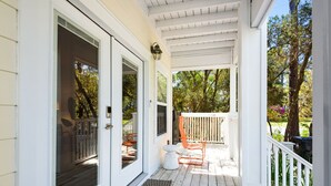 A covered porch with a white railing, a wooden deck, and a view of trees and a garden. - Family & Pet-Friendly 30A Villa – Private Pool w/Heat, 3BR, 5 Bikes, Near Beach (Santa Rosa Beach)