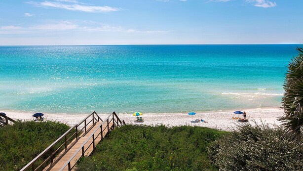 A beach with clear turquoise waters, a wooden walkway, and several beach umbrellas. - Family & Pet-Friendly 30A Villa – Private Pool w/Heat, 3BR, 5 Bikes, Near Beach (Santa Rosa Beach)