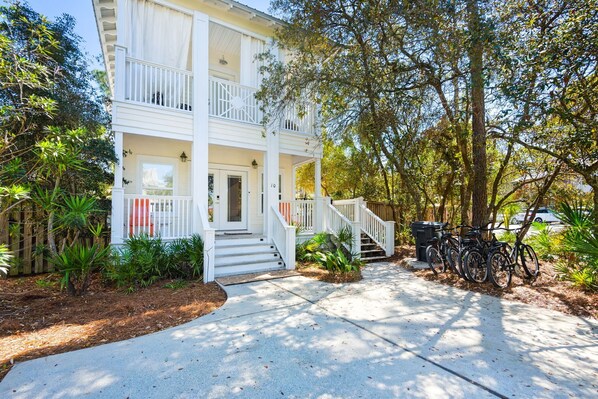 A two-story house with a front porch, steps leading to the entrance, and a bicycle parked outside.