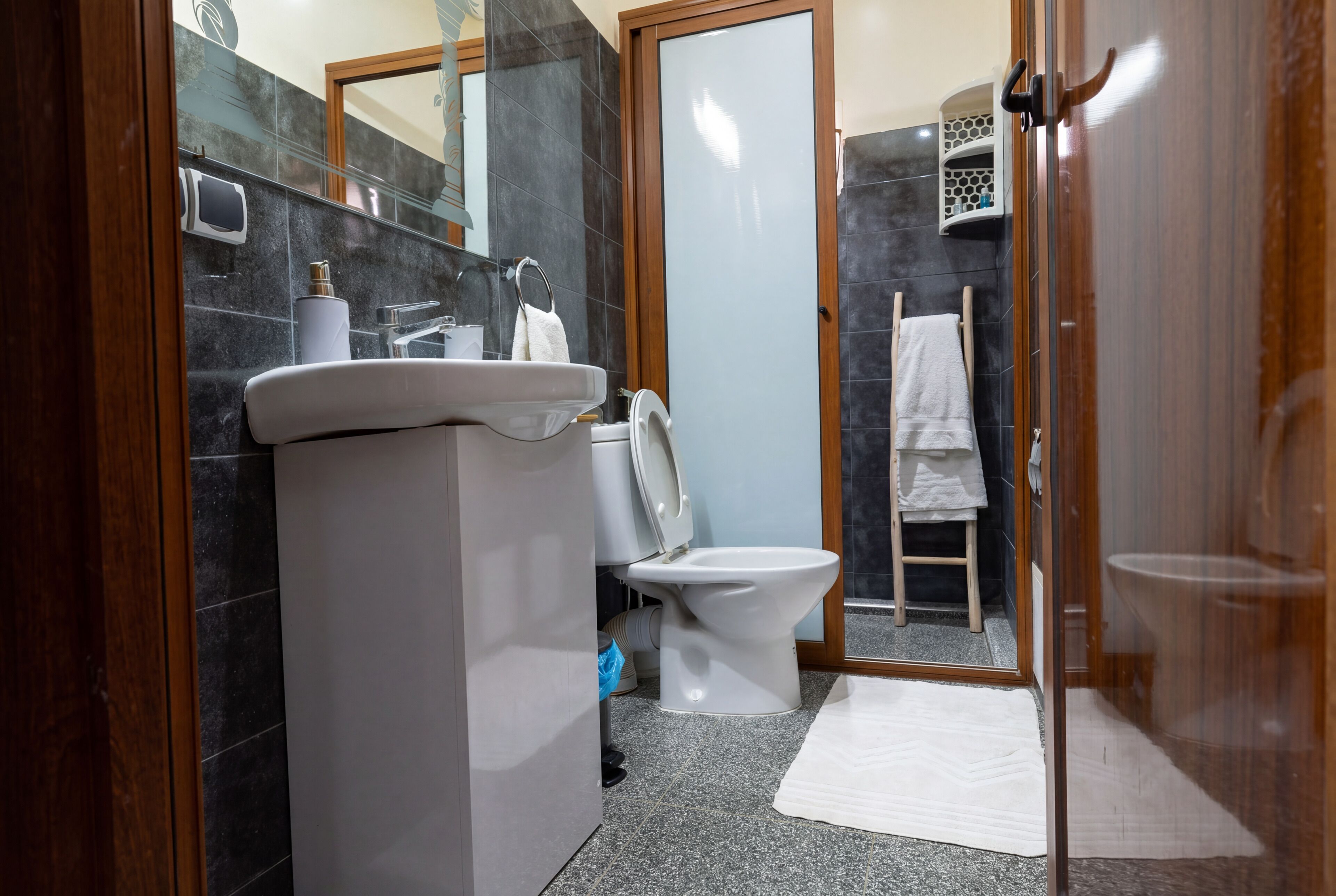 A bathroom with a toilet, sink, mirror, and towel rack.