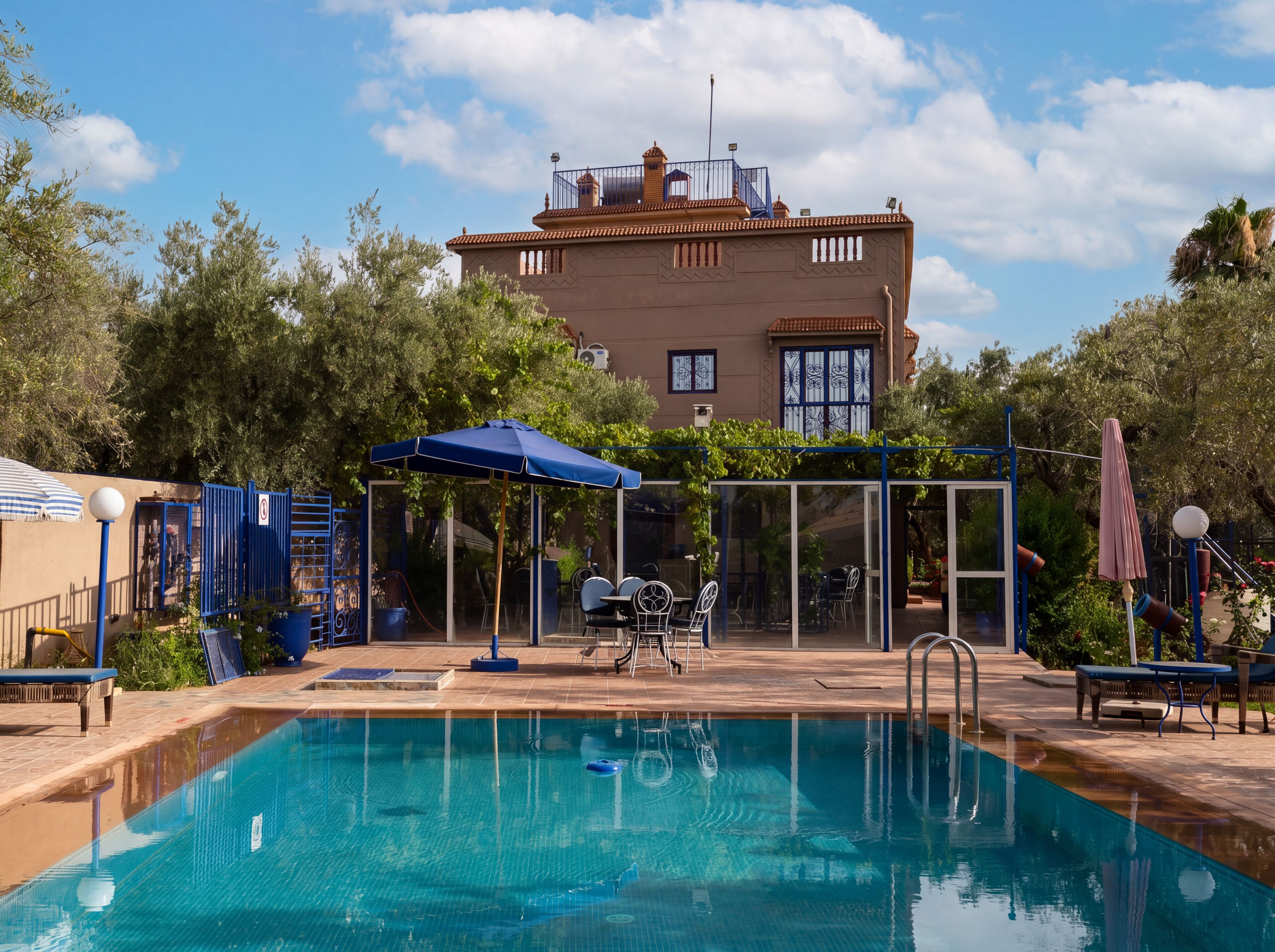 Uma piscina com cobertura de vidro, área de estar externa e um edifício ao fundo.