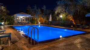 A swimming pool with a blue-lit edge, surrounded by outdoor seating and a building with a covered patio. - Ferme D'hôte Eco Farm Tayssir (Ait Sidi Daoud)
