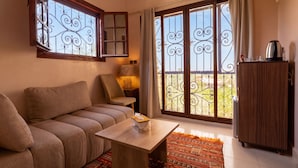 Un salon comprenant un canapé, une table, une lampe et une vue dégagée sur l’extérieur grâce à une grande fenêtre donnant sur un balcon.