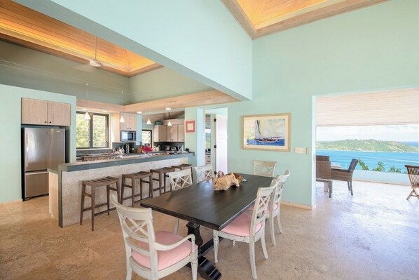 A spacious kitchen with a central island, wooden cabinets, and a view of the ocean.