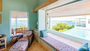 Ein Zimmer mit Meerblick, einer Holzbalkendecke und einer Sitzecke mit Kissen.
