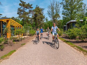 A pathway with people riding bicycles, surrounded by greenery and modern buildings. - Well-kept Chalet in a Holiday Park, Adjacent to the Hoge Veluwe National Park (Arnhem)