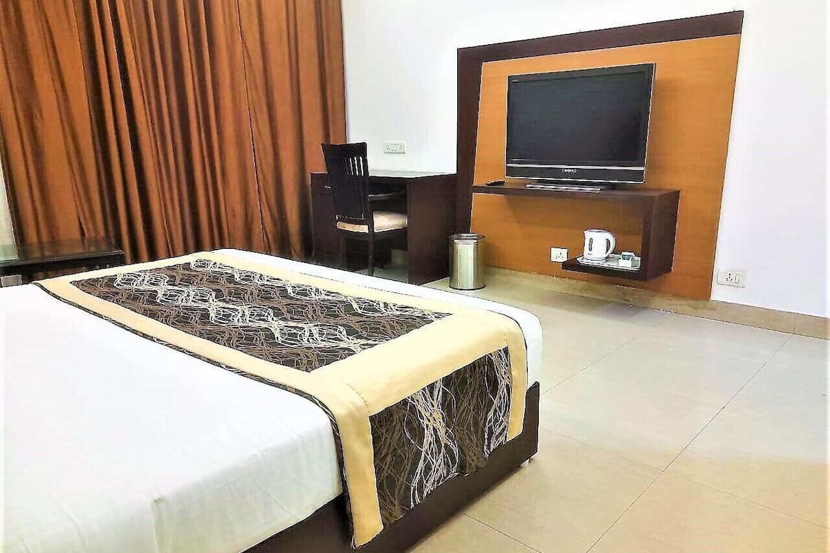 A hotel room with a bed, a television, a desk, and a coffee machine.