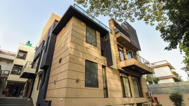 A modern two-story building with a flat roof, large windows, and a balcony.