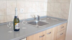 Una cocina con un lavabo, una botella de vino y dos copas de vino sobre la encimera.