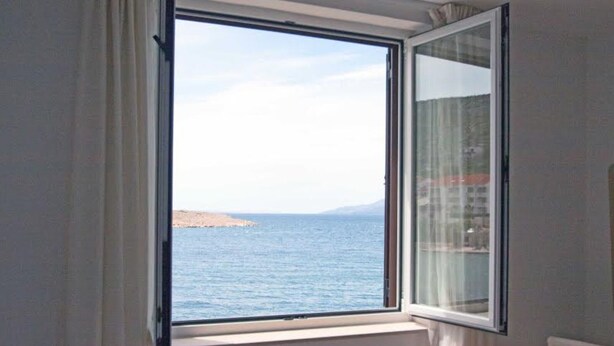 A room with a window overlooking a body of water and a distant landmass. - Beachfront Apartments Tamarix - Studio Apartment 3 (Posedarje)
