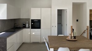 Eine moderne Küche mit weißen Schränken, einem schwarzen Backofen und einem Holzespeisetisch mit Stühlen.