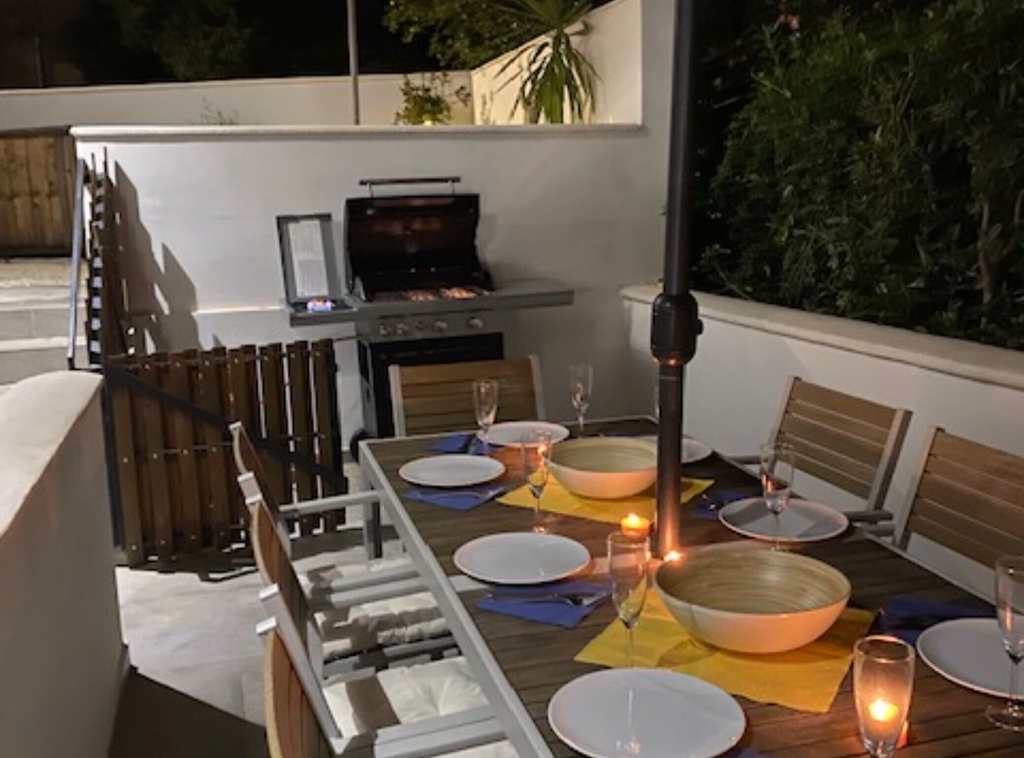 Un espace extérieur aménagé pour les repas, avec une table pour deux, un barbecue et une vue sur le jardin.