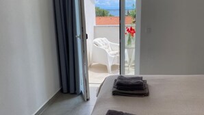 Ein Hotelzimmer mit Bett, einem Fenster mit Vorhängen und Blick auf den Balkon.