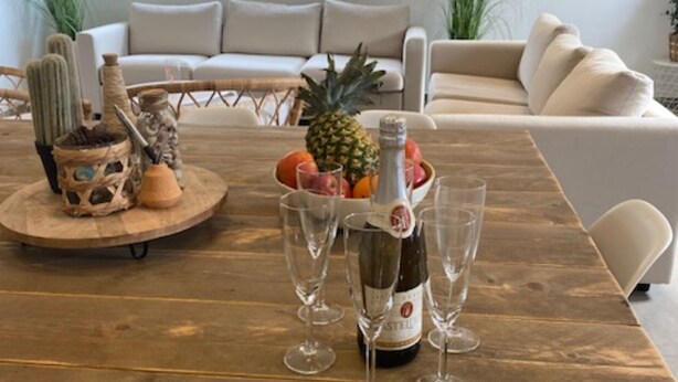 Ein Holztisch mit einer Weinflasche, Gläsern und einer Obstschale.