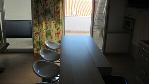 A kitchen with a long countertop, a microwave, and a window with a view of a tiled roof. - Guest House Villa Daniel - Two Bedroom Apartment with Balcony (Omis)