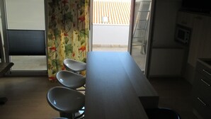 A modern kitchen with a long countertop, a microwave, and a sliding glass door leading to a balcony. - Double Room with Balcony 1 (Omis)