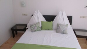 A bed with a white and green bedspread, two pillows, and a headboard. There are two bedside tables, one on each side of the bed. - Double Room with Balcony 1 (Omis)