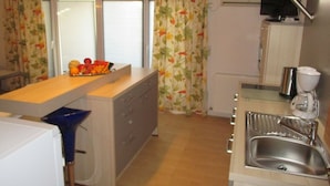 A compact kitchen with a wooden countertop, a sink, a small refrigerator, and a microwave. There is a fruit bowl on the countertop and a television mounted on the wall. - Double Room with Balcony 1 (Omis)