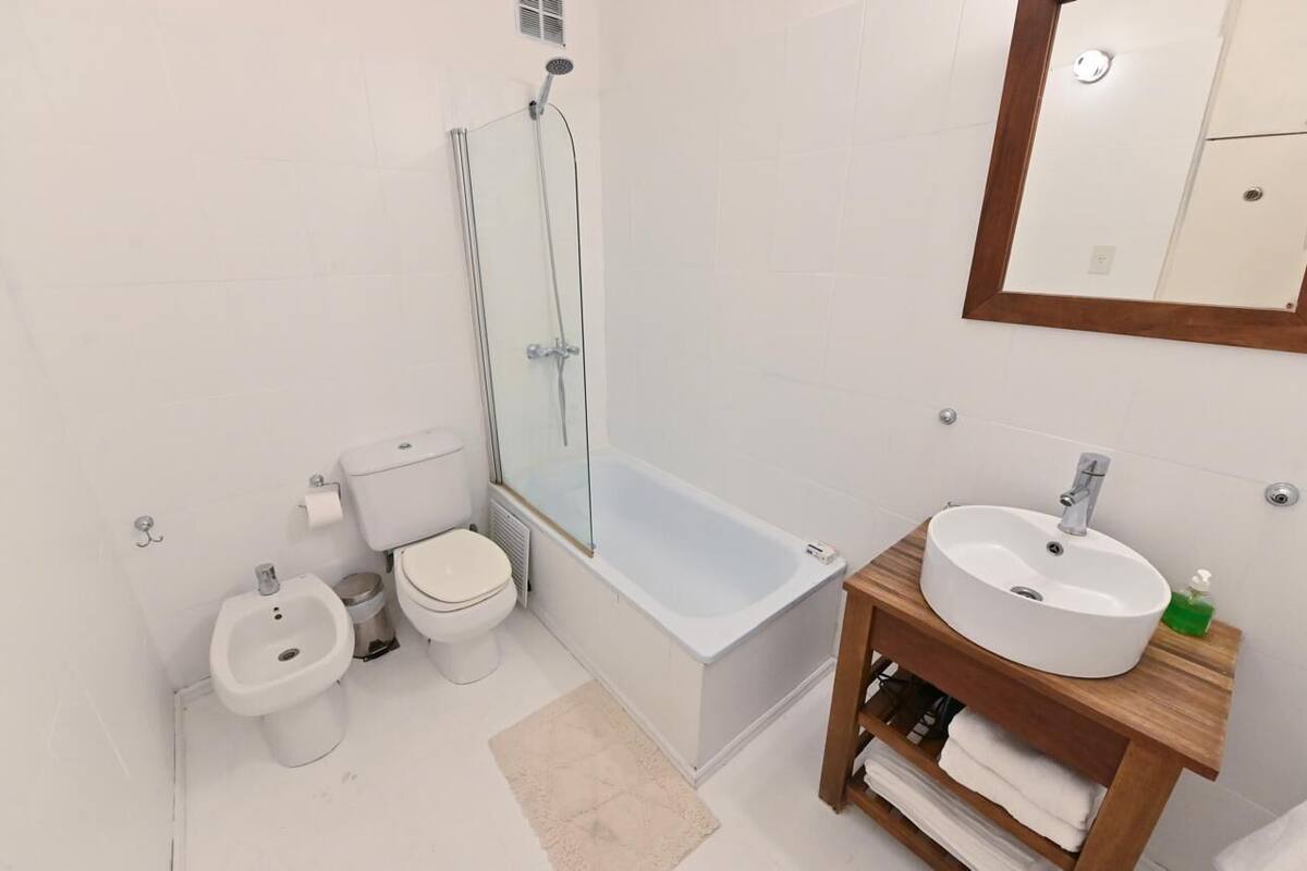 Ein modernes Badezimmer mit Toilette, Bidet, Badewanne und einem Holzlagerfeld mit Waschbecken.