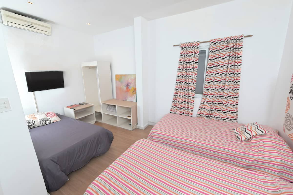Ein Schlafzimmer mit zwei Betten, einem Fernseher, einem Kleiderschrank und einem Schreibtisch.