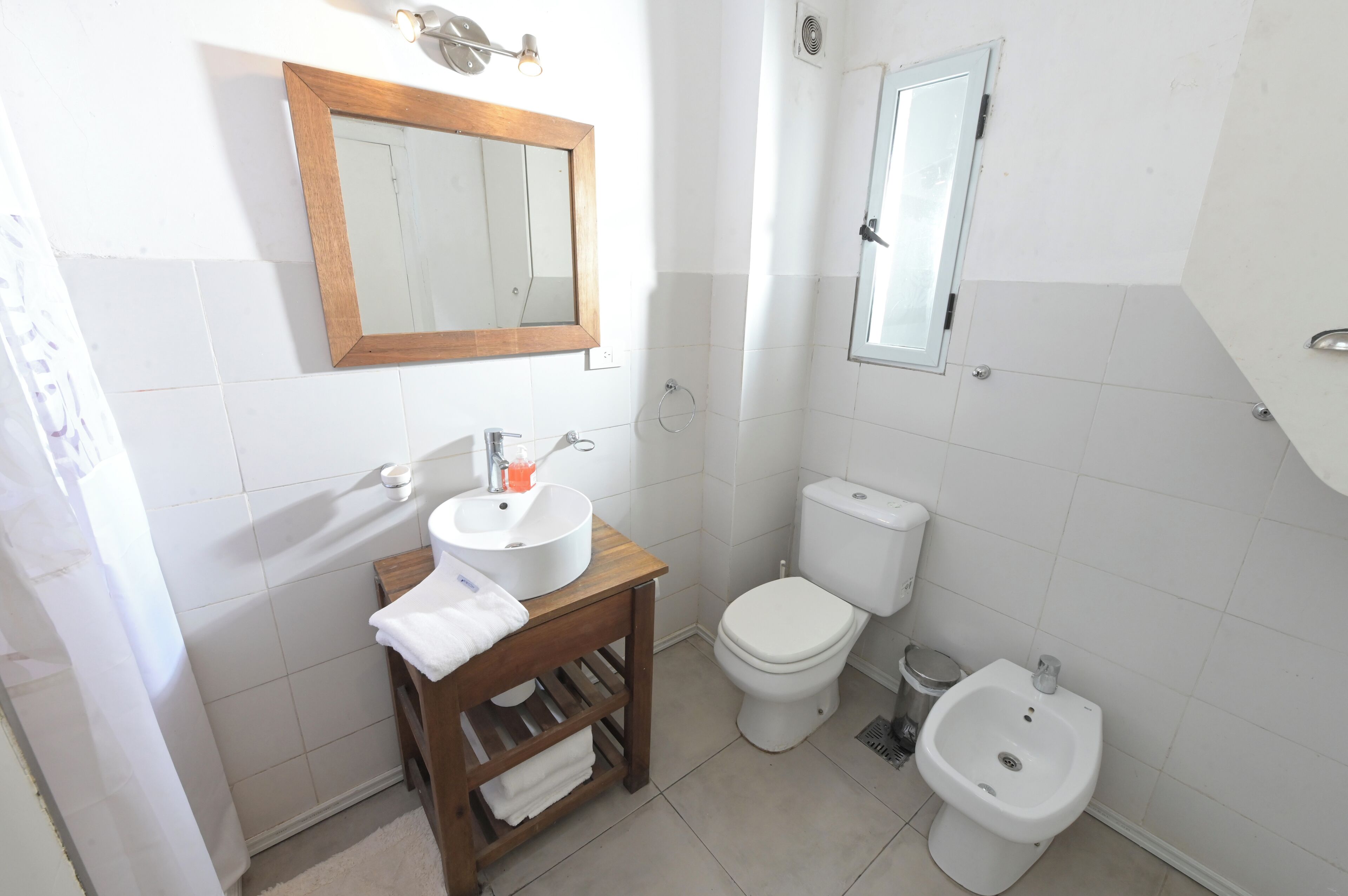 A bathroom with a sink, toilet, bidet, and a mirror.