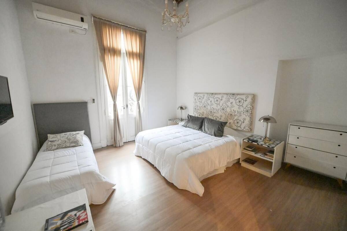Ein Schlafzimmer mit zwei Betten, einem Nachttisch, einer Kommode und einem Deckenventilator.