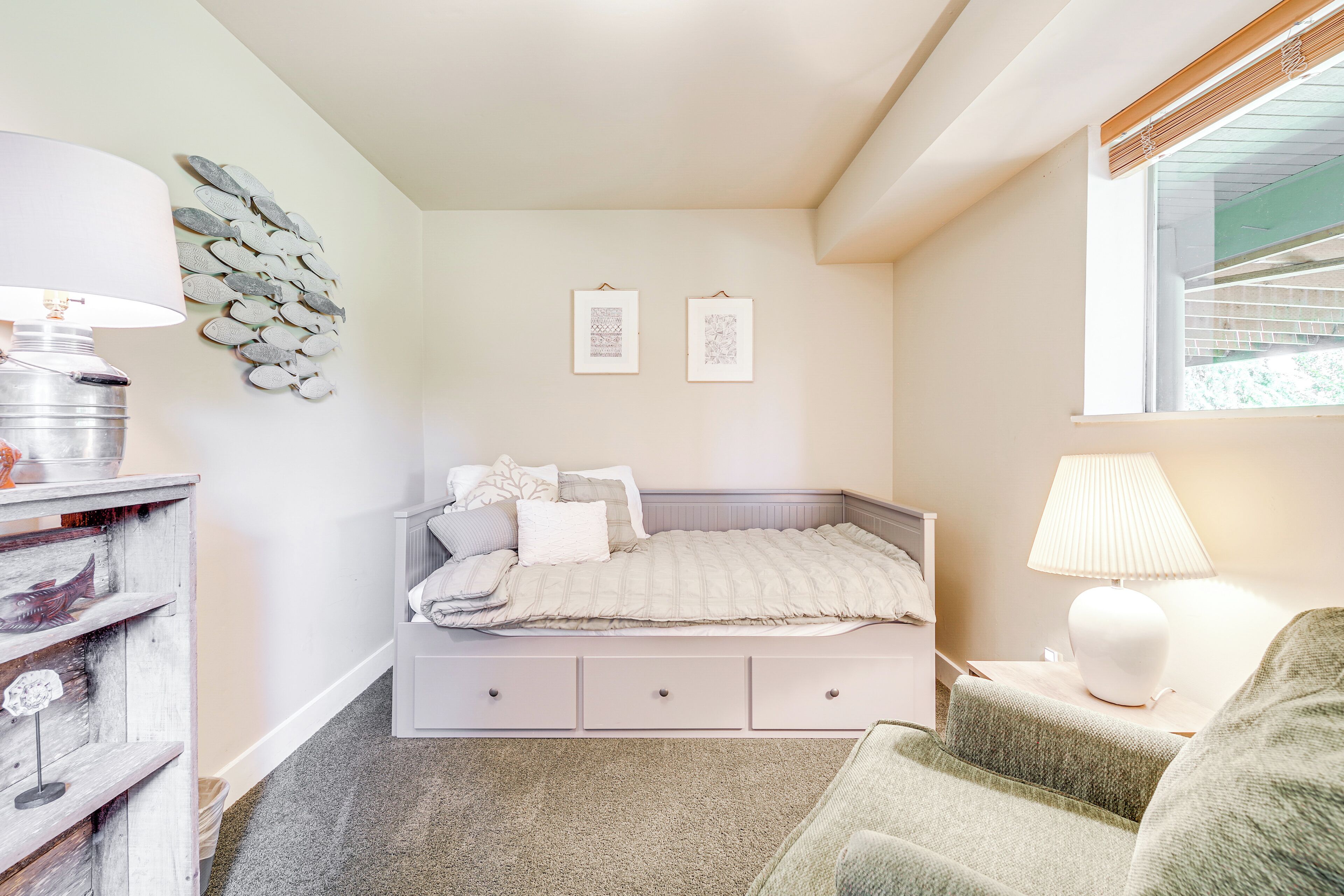 Un dormitorio con cama, mesita de noche, lámpara, decoración mural y una ventana.