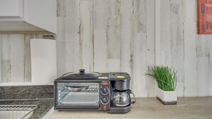 A kitchen with a built-in toaster oven and coffee maker, a potted plant, and a wooden wall. - Pet-Friendly Picayune Tiny Home Near Space Center! (Picayune)