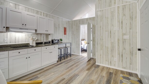 A modern kitchen with white cabinetry, a microwave, and a bar stool. - Pet-Friendly Picayune Tiny Home Near Space Center! (Picayune)