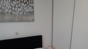 Een opgemaakt bed met witte lakens en twee opgerolde handdoeken.