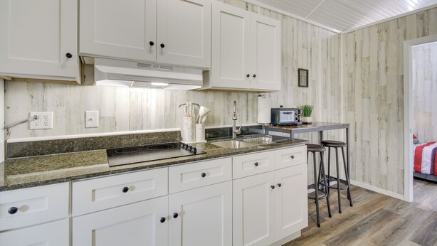 A kitchen with white cabinets, granite countertops, and a built-in range hood. - Cozy Picayune Tiny Home Rental ~ 4 Mi to Downtown! (Picayune)