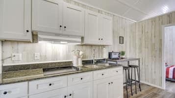 A kitchen with white cabinets, granite countertops, and a built-in range hood.
