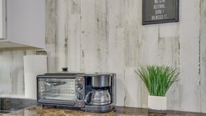 A kitchen with a built-in toaster oven, a coffee maker, and a potted plant on the counter. - Cozy Picayune Tiny Home Rental ~ 4 Mi to Downtown! (Picayune)