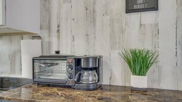 A kitchen with a built-in toaster oven, a coffee maker, and a potted plant on the counter.