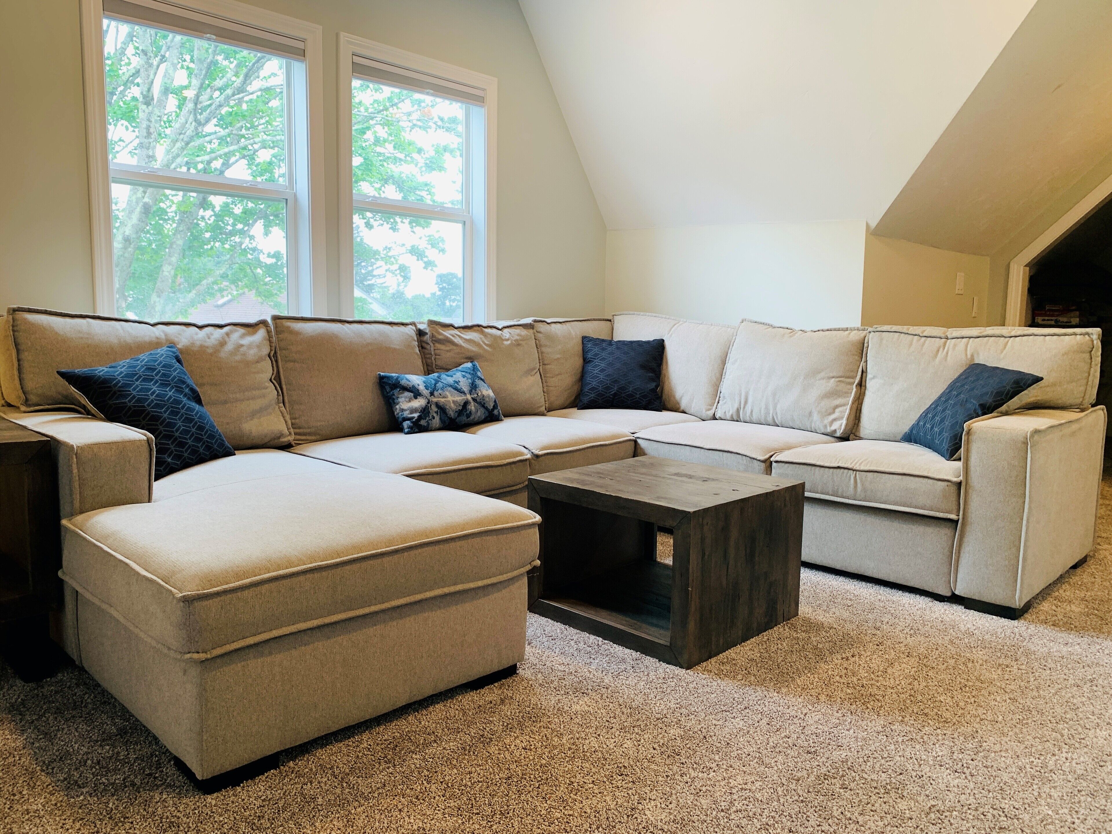 A sectional sofa with multiple cushions, a small coffee table, and a carpeted floor.