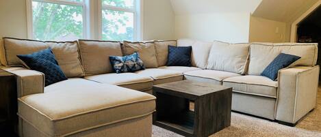 A sectional sofa with multiple cushions, a small coffee table, and a carpeted floor.